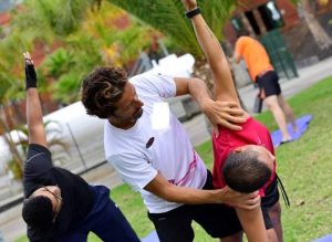 Instructor corrige a una alumna en una clase de yoga al aire libre